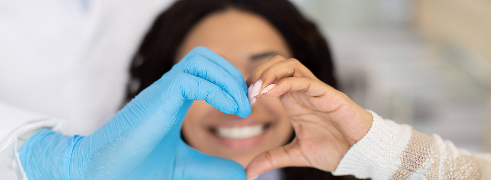 The image shows a group of people, possibly professionals given their attire and the setting that appears to be an office or professional environment. They are gathered around a table with a laptop on it, engaged in what seems to be a discussion or meeting.