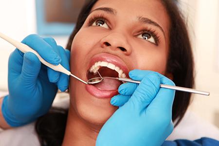 A woman receiving dental care with a dental hygienist performing the procedure.