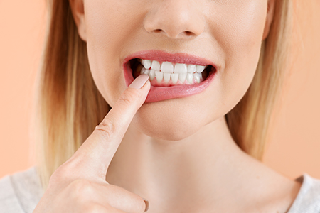 The image features a woman with her finger on her teeth, possibly brushing them, against a light-colored background.