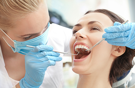 A dentist performing dental work on a patient s teeth while wearing protective gear.